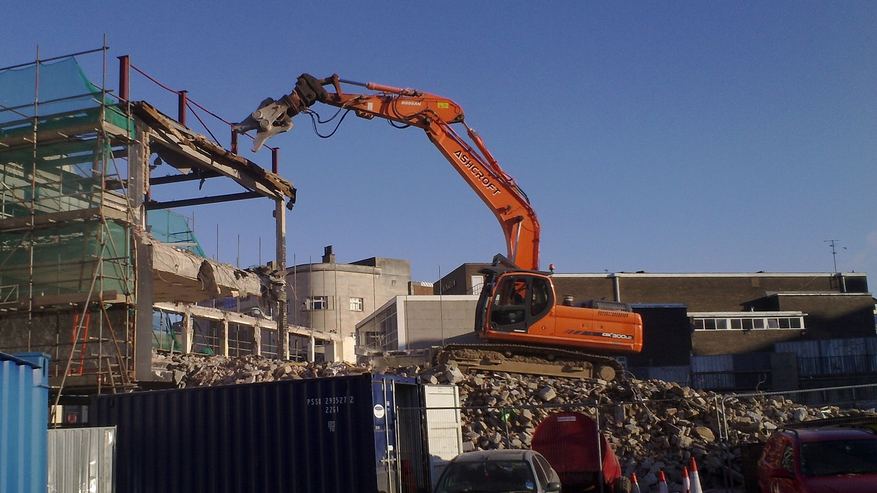 excavator carrying out the demolition of a large commercial building